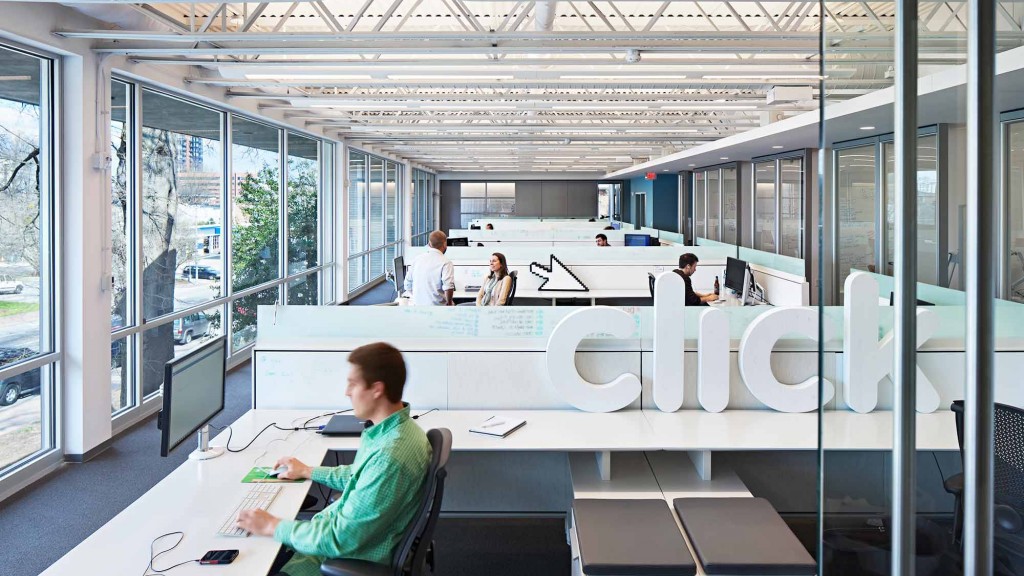 A group of people sitting at a table in a room with windows.