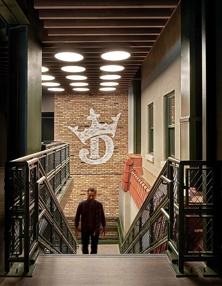 A person walking up a flight of stairs with a brick brand design wall behind