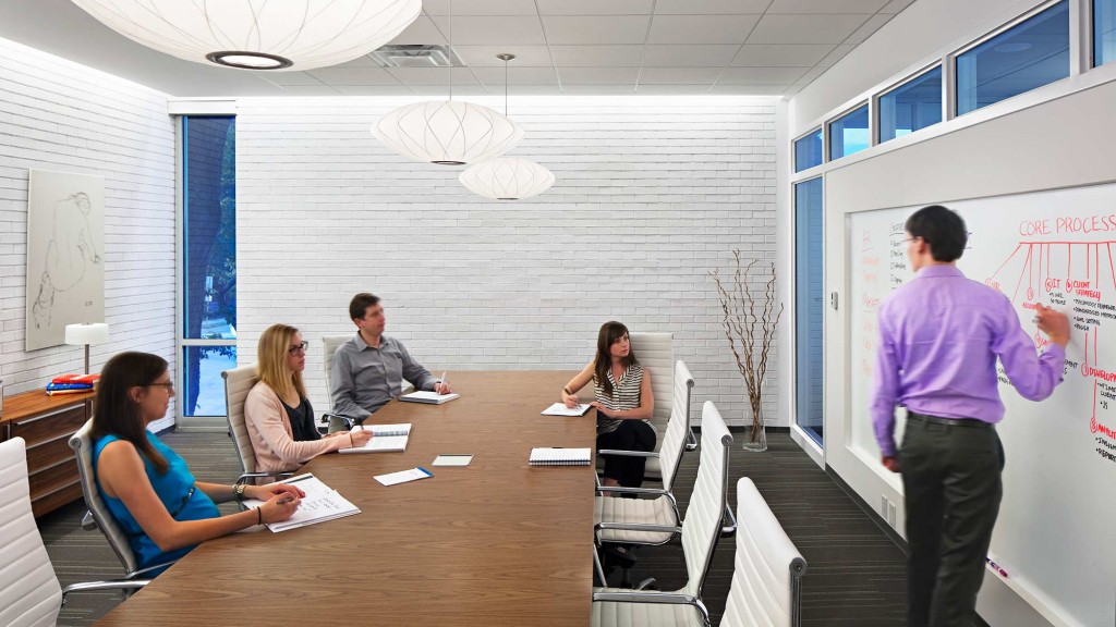 A person standing in front of a table with people sitting at it.