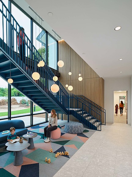 A person and a child sitting on a couch in a room with stairs.