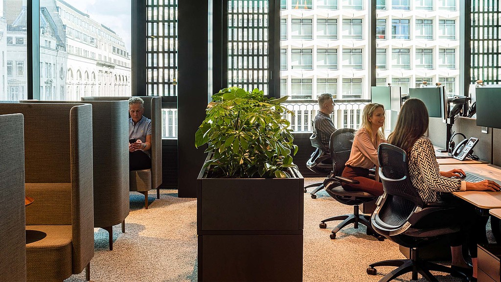 A group of people sitting at a table in a room with windows.