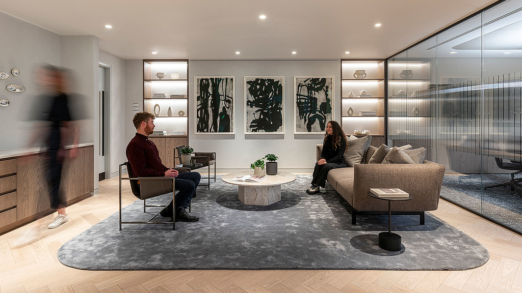 A man and a woman sitting in a room with a glass wall.