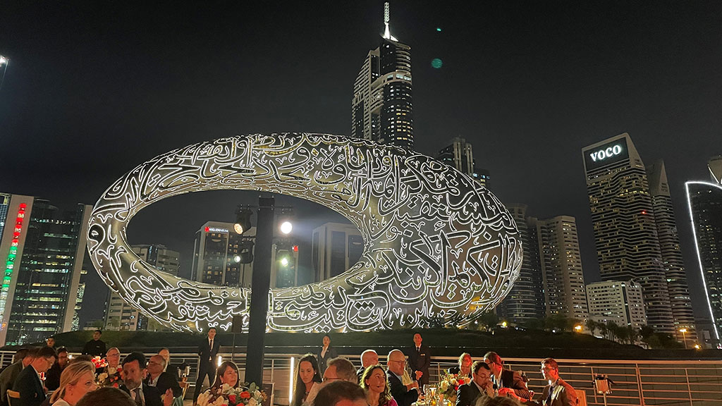 A crowd of people in front of a large sculpture.