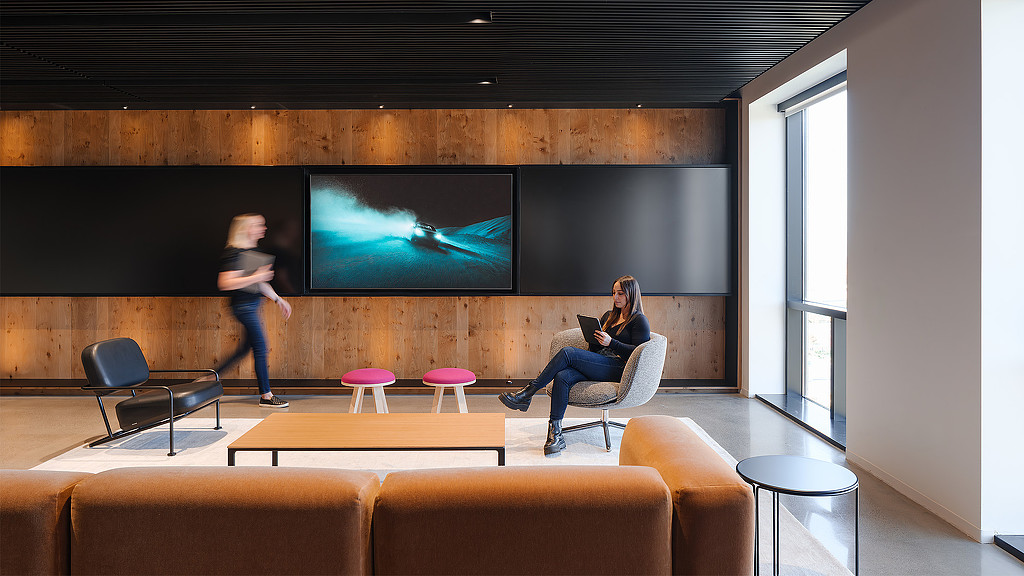 A person sitting on a chair in front of a screen.