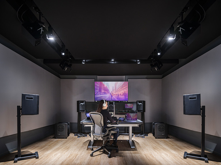 A person sitting at a desk in a room with a projector screen.