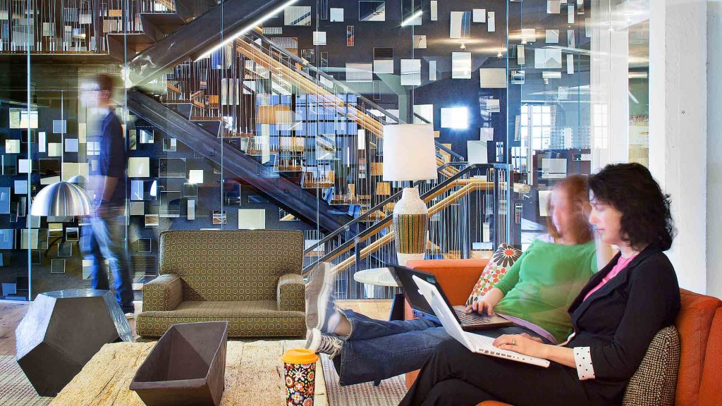 A man and woman sitting on a couch looking at a laptop.