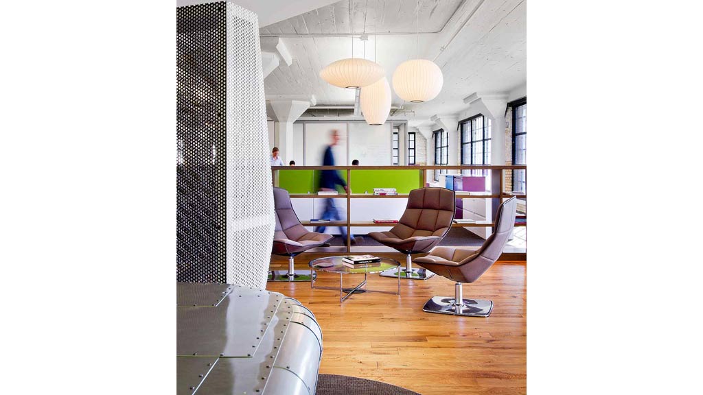 A room with a couch and a table with a person standing in the background.