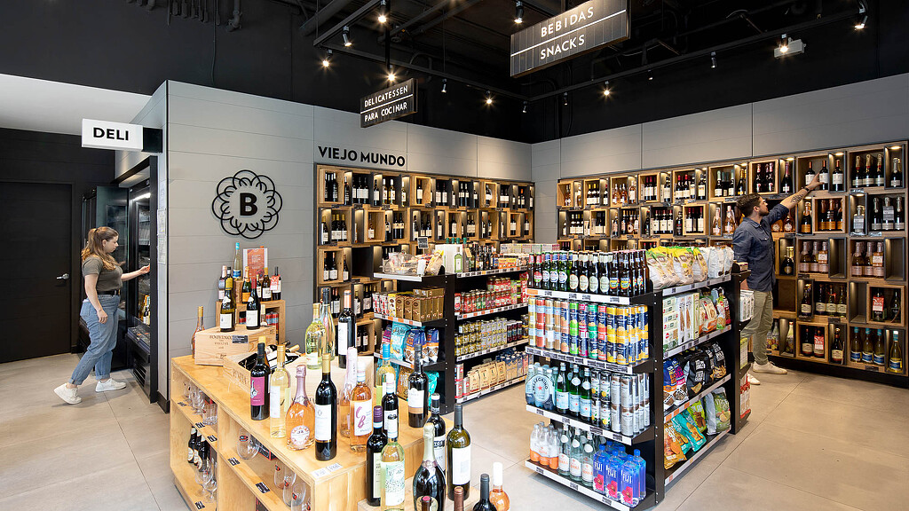 A man and woman standing next to a counter with bottles of wine.