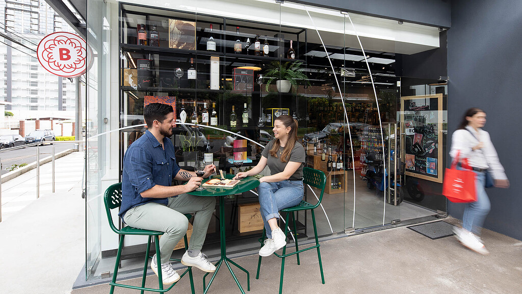 A man and woman sitting at a table outside a building.