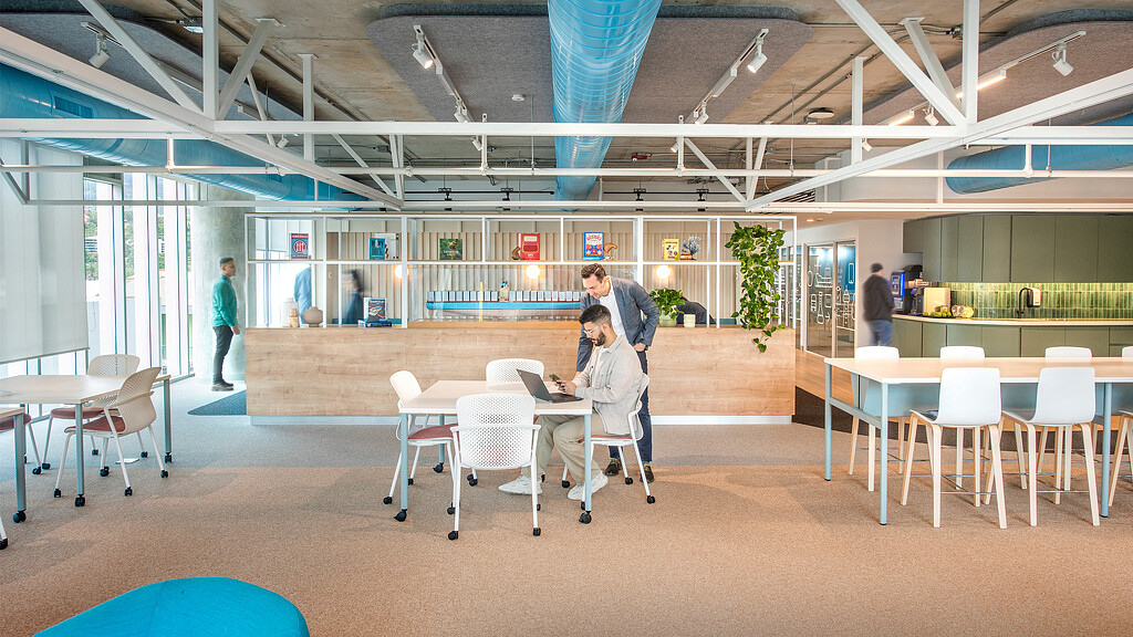 A man and woman sitting at a table in a large room with tables and chairs.