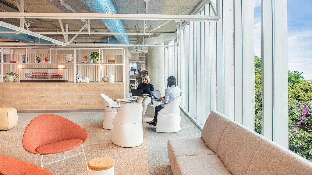 A couple of women sitting at a table in a room with a large window.
