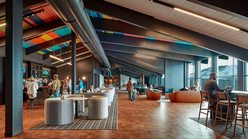 A group of people in a large room with tables and chairs.