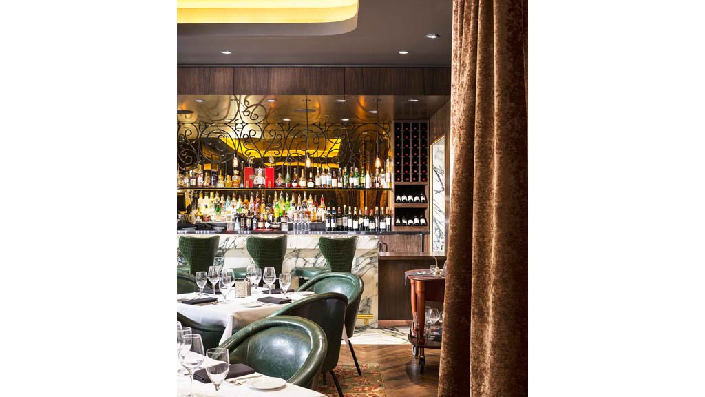 A bar with green chairs and tables.