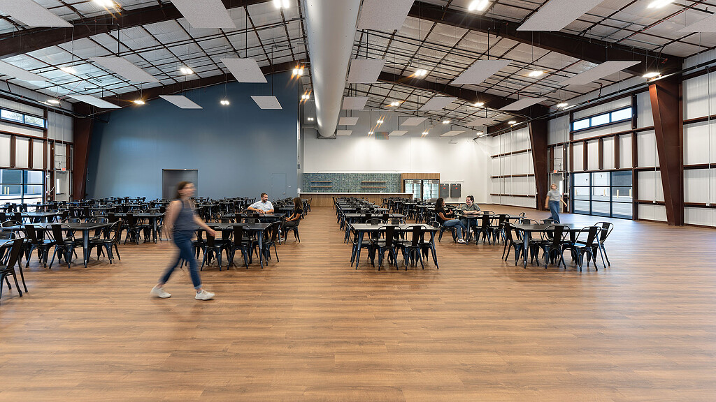 A person walking in a large room with tables and chairs.