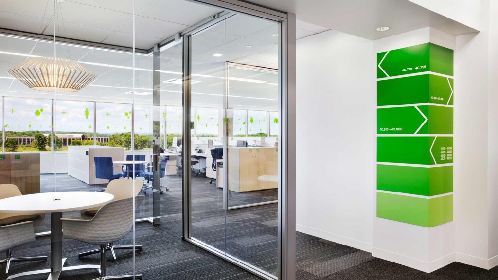 A glass walled office with a glass door and a table and chairs.