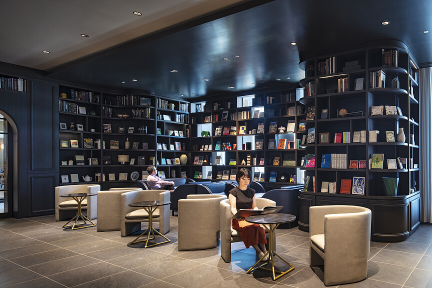A couple of people sitting in a room with shelves of books.