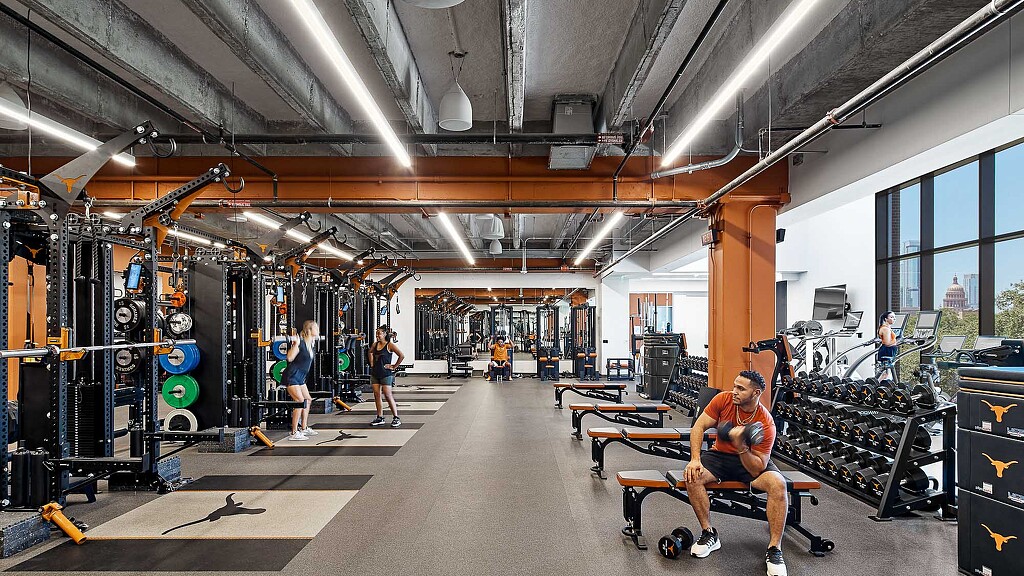A student athlete sitting on a bench in a gym.