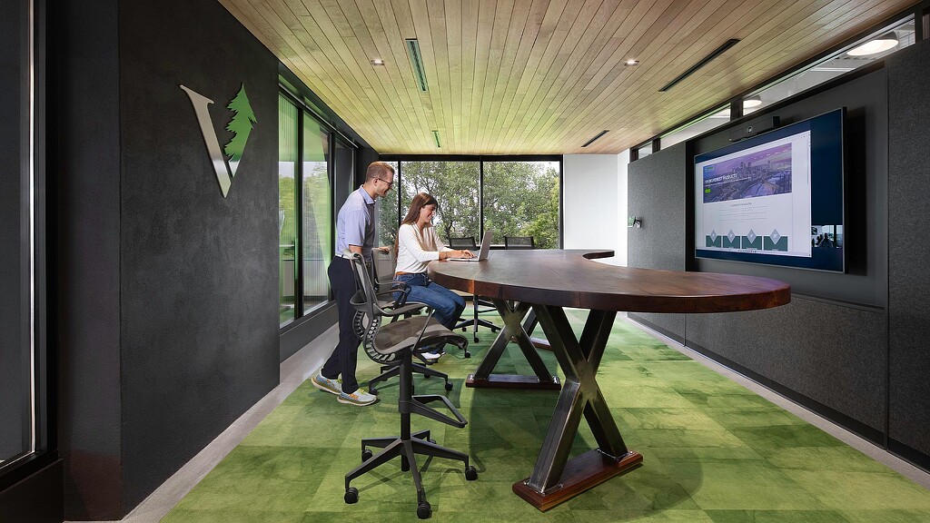 A man and a woman in a room with a large screen.