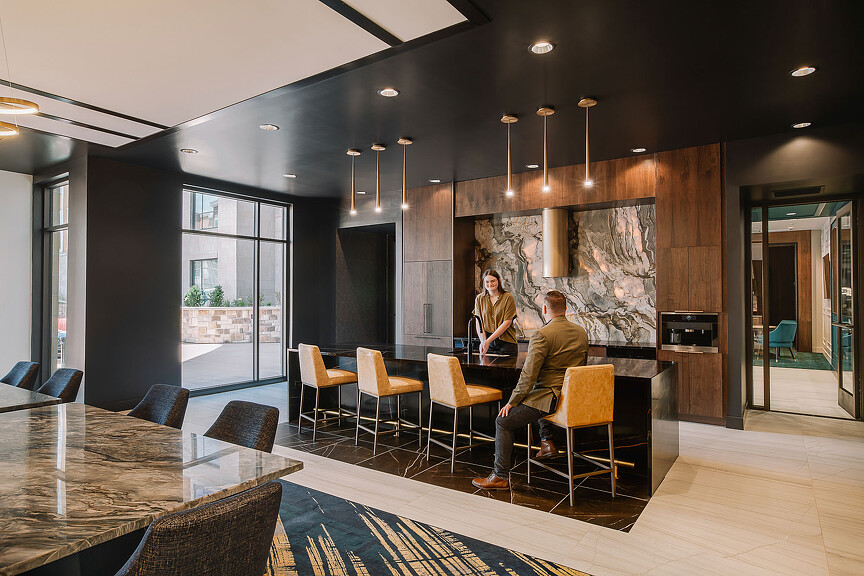 Two people hanging out in Galleria Residences amenity space with bar table and stools