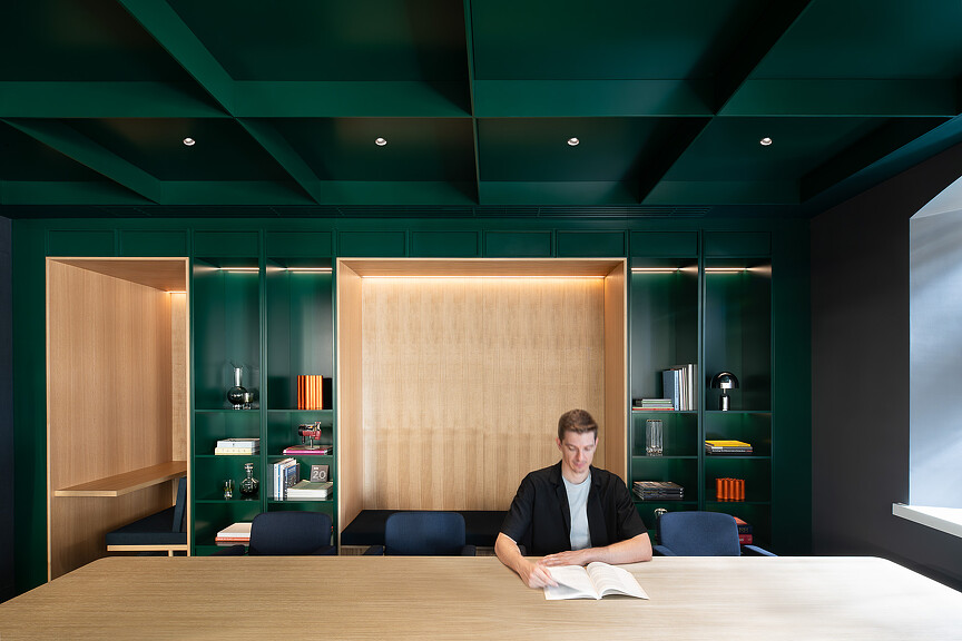 A man sitting reading in Hilson Moran’s Living Lab room with green walls
