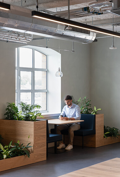 A man sitting at Hilson Moran’s Living Lab booth by window