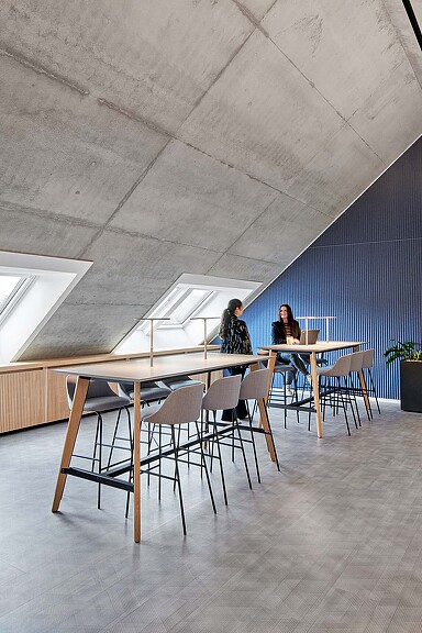A couple of people sitting at a table with chairs and a large white ceiling.