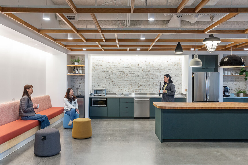 A couple of women sitting on a couch in a room with a bar and a table.