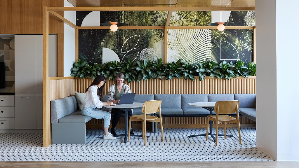 A man and woman sitting at a table with a laptop.