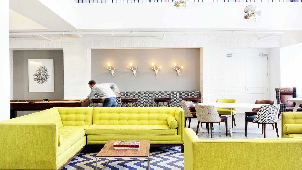 A person standing in a room with a couch and tables.