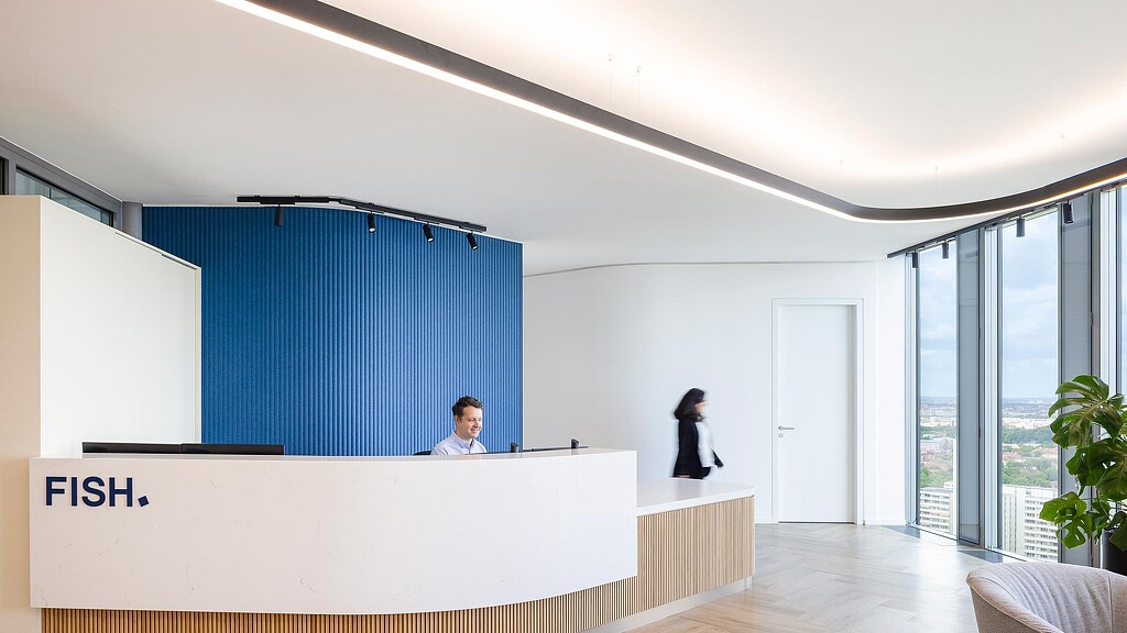 A man and a woman in a room with a large blue curtain.