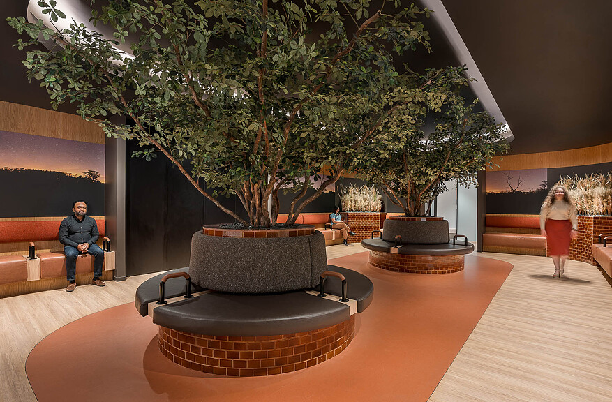 A man and woman sitting on a couch in a room with a tree.