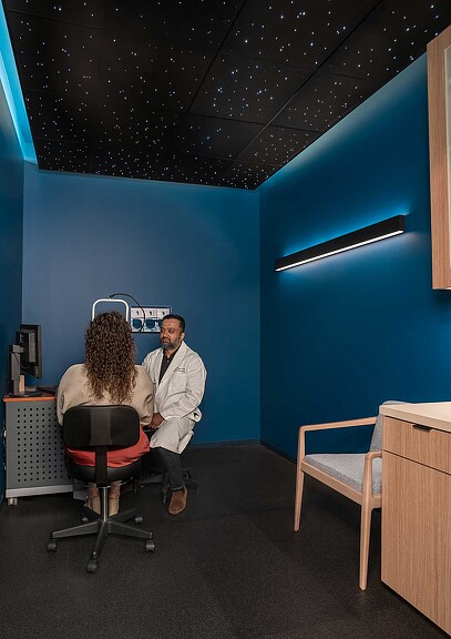 A man sitting in a chair next to a woman sitting at a desk.