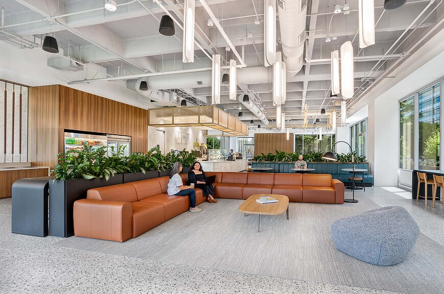 A couple of people sitting in a room with a large couch and a table.