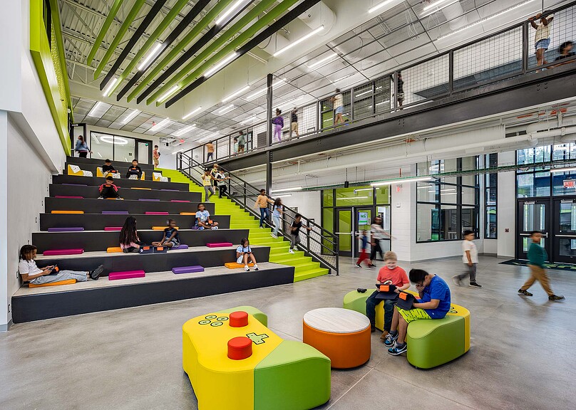 People sitting on benches in a large room with a large group of people.