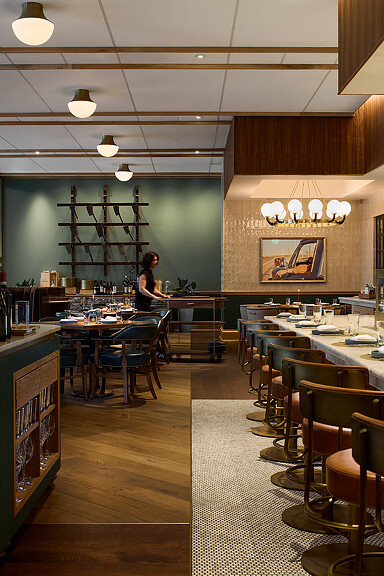 A person standing in a room with tables and chairs.