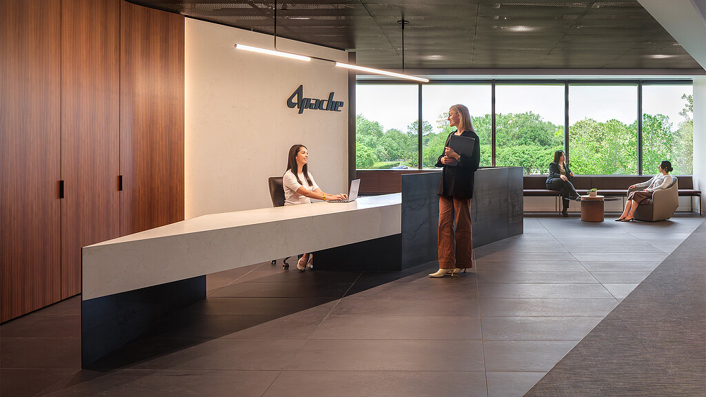 A person standing in a room with people sitting on a bench.