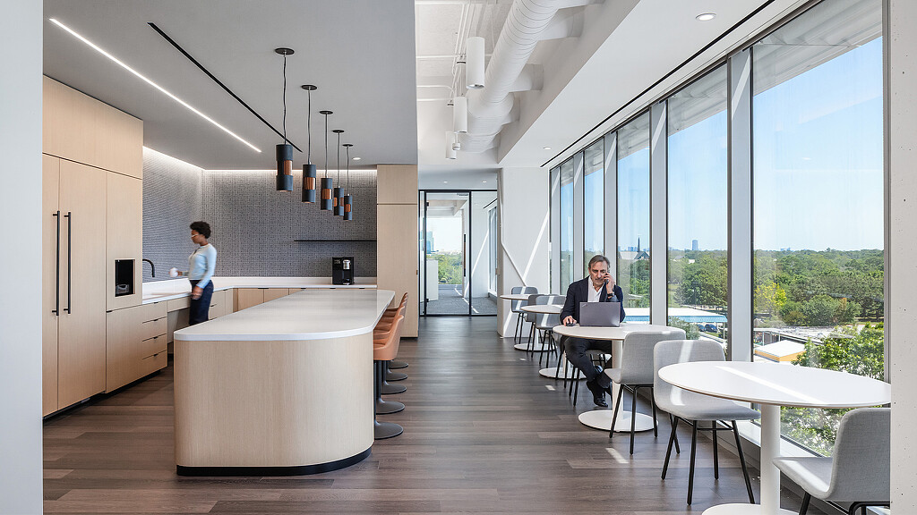A woman standing next to a man seated at a table.