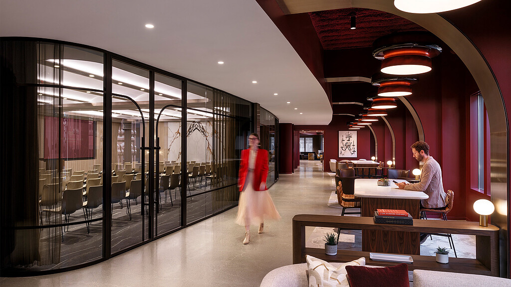 A man and woman walking in a room with glass walls and tables.