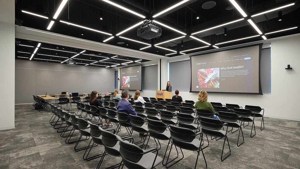 A group of people sitting in a room with a projector screen.