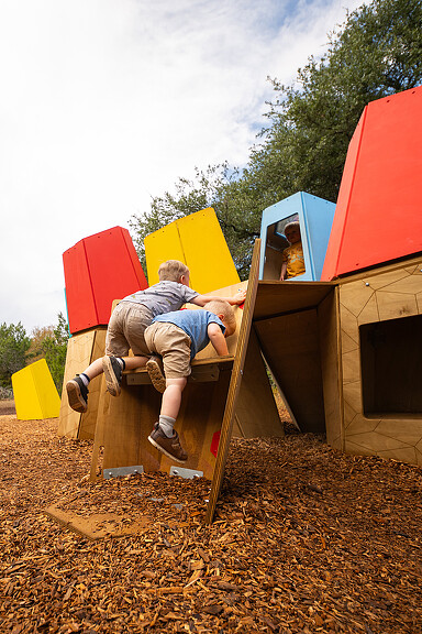 A person and a child playing on a play structure.