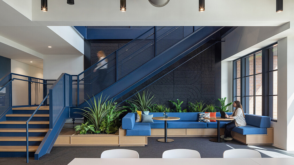 A person sitting on a couch in a room with a staircase.