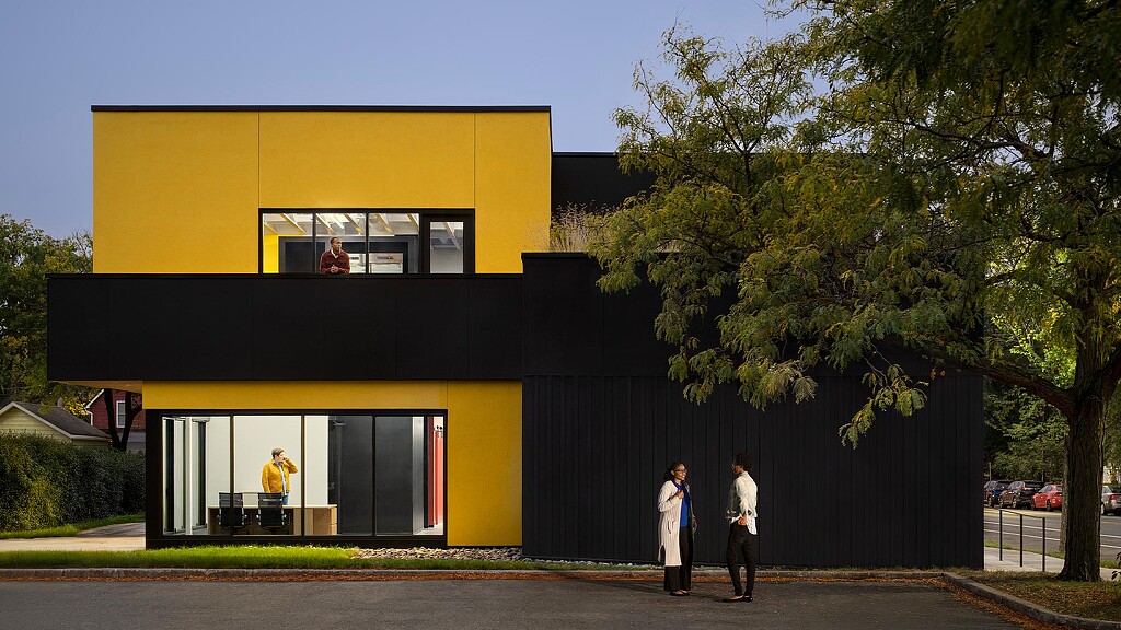 A yellow building with a black fence.