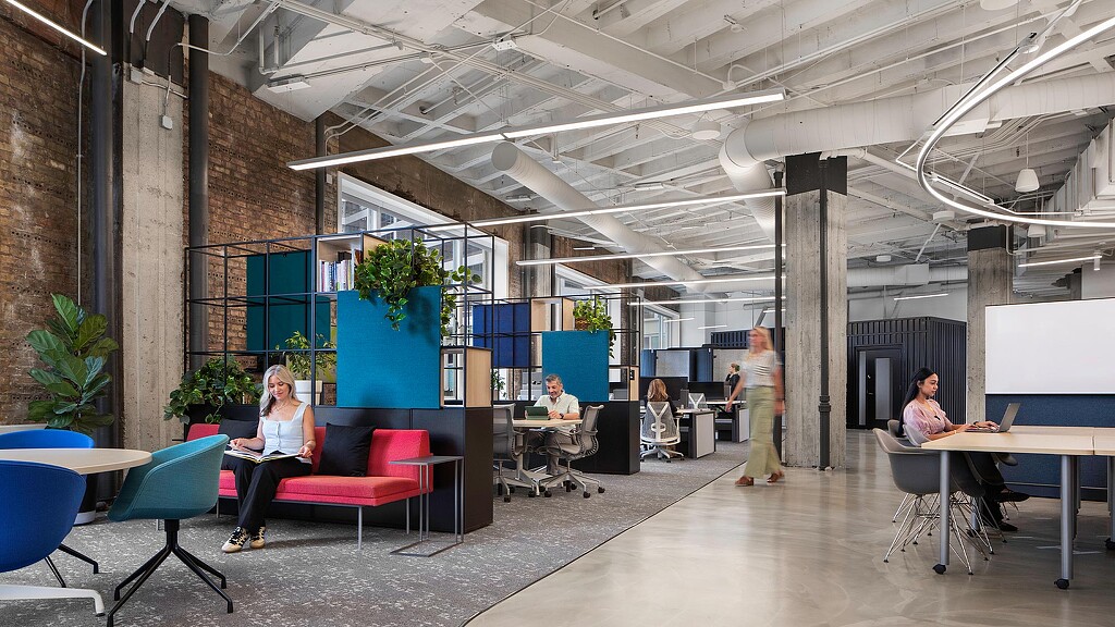 A group of people sitting in a room with tables and chairs.