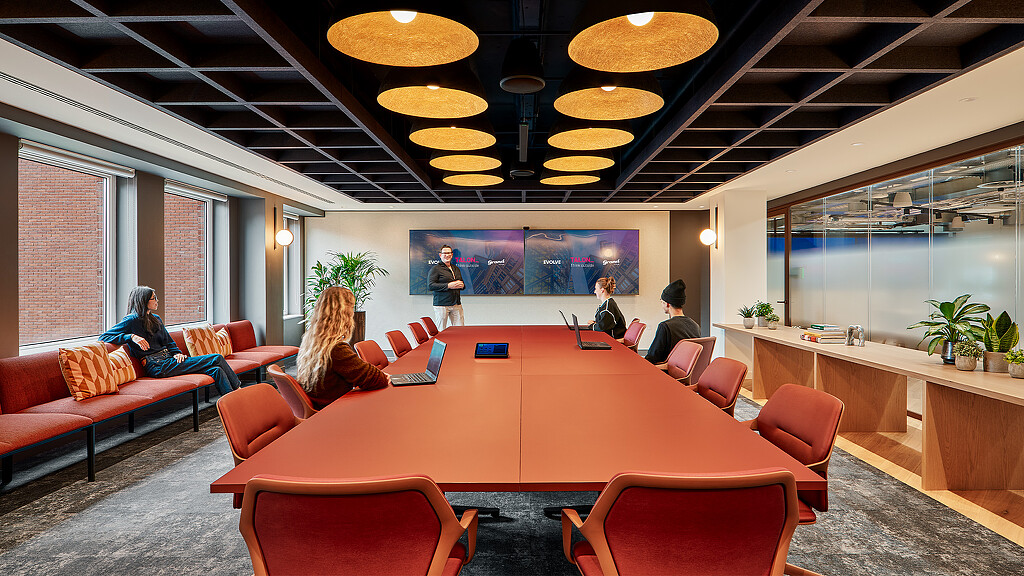 A group of people sitting in a room with a large screen.