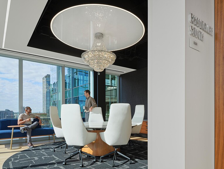 A couple of men sitting at a table in a room with a large window and a large chan.