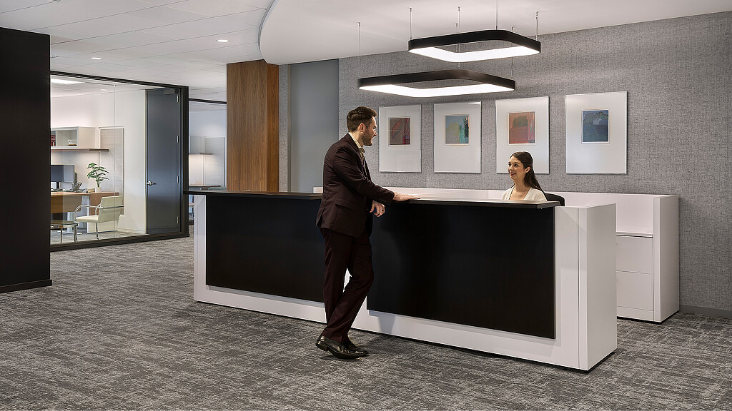 A man and a woman standing in a room with a large black counter.