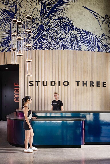 A man and woman sitting at a table in front of a wall with art on it.