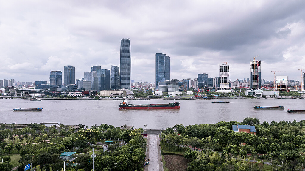 A city skyline with a river and boats.