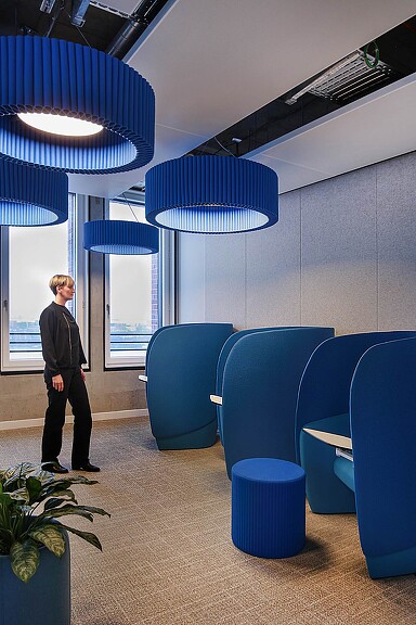A person standing in a room with blue chairs.