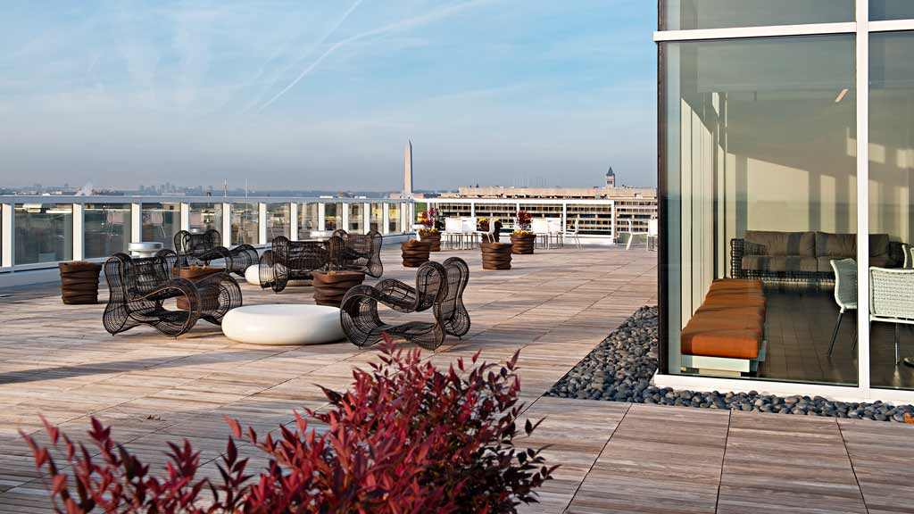A patio with chairs and tables and a view of a city.